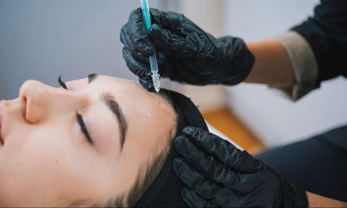 Injections de toxine botulique sur le front d'une patiente allongée en cabinet