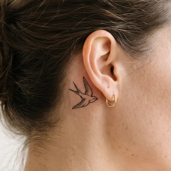 Petite hirondelle tatouée derrière l’oreille, taille XS