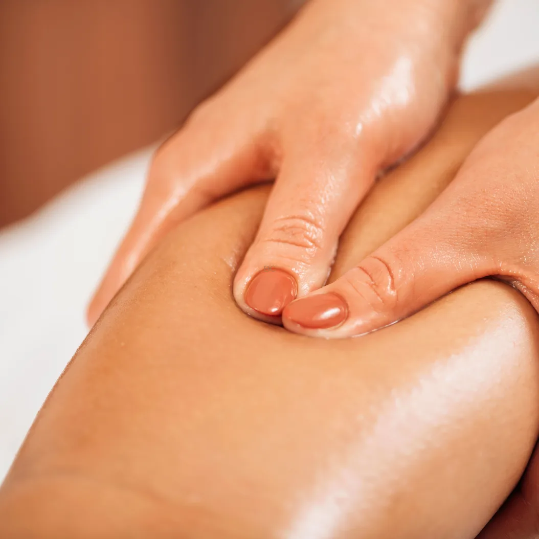 Drainage lymphatique classique : pression manuelle glissée sur la jambe, geste lent et léger