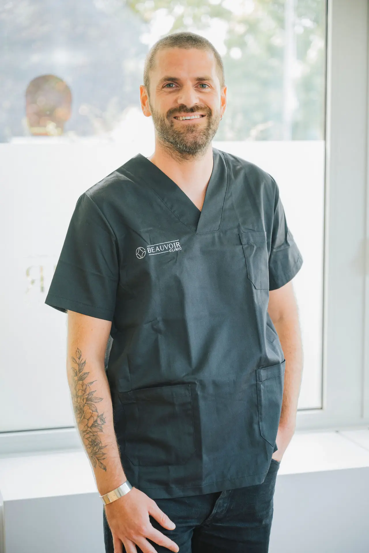 Professionnel médical souriant en uniforme noir.
