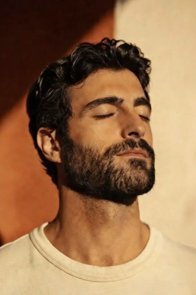 Homme barbu profitant du soleil les yeux fermés